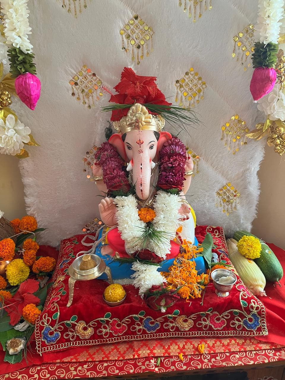 Ganpati idol adorned with fresh white sevanti, celosia and marigold malas